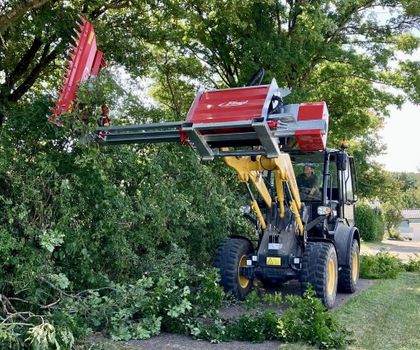 Der Radlader Komatsu WA80M-8 im Einsatz Der Radlader Komatsu WA80M-8 im Einsatz, in dem er mit seinem Anbaugeräte eine Hecke schneidet