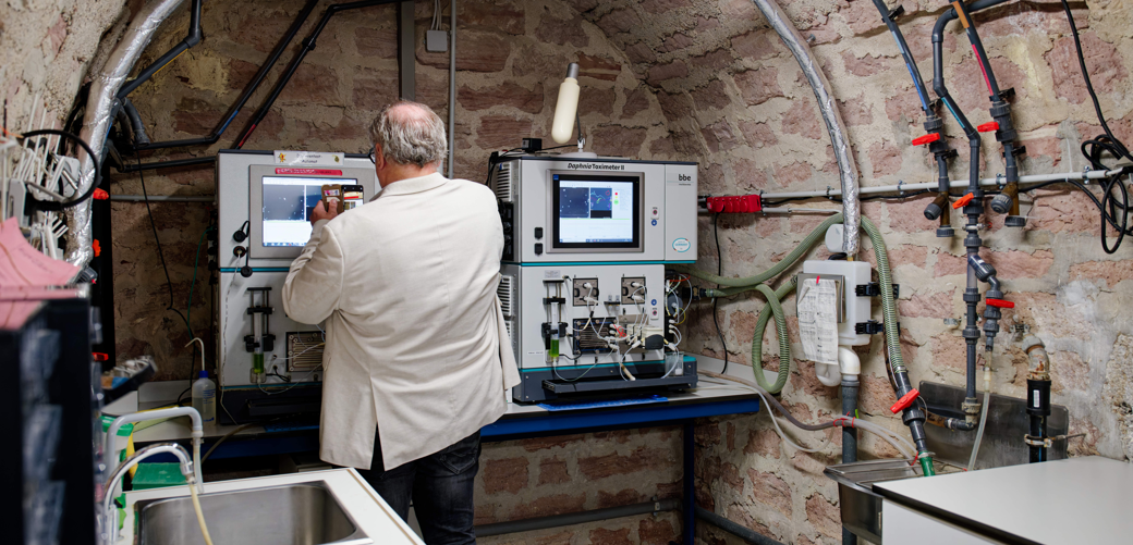 Wasserqualität des Rheins seit 30 Jahren kontrolliert Ein Besucher steht bei einem Rundgang durch die Rheingütestation an einem Daphnientoximeter. Die Rheingütestation ist ein zentraler Bestandteil des Gewässerschutzes am Rhein. Sie überwacht kontinuierlich die Wasserqualität und leistet damit seit 30 Jahren einen wichtigen Beitrag zum Umweltschutz und der Sicherheit der Trinkwasserversorgung.