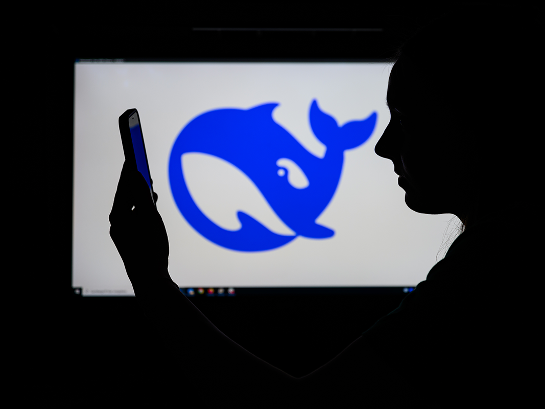 Das Logo des chinesischen KI-Start-ups DeepSeek auf einem Computerbildschirm zu sehen, während davor eine Frau auf ihr Smartphone schaut. Das Logo des chinesischen KI-Start-ups DeepSeek auf einem Computerbildschirm zu sehen, während davor eine Frau auf ihr Smartphone schaut.