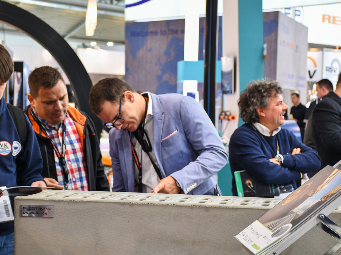 Besucher aur einer Messe begutachten Produkte von BG-Graspointner