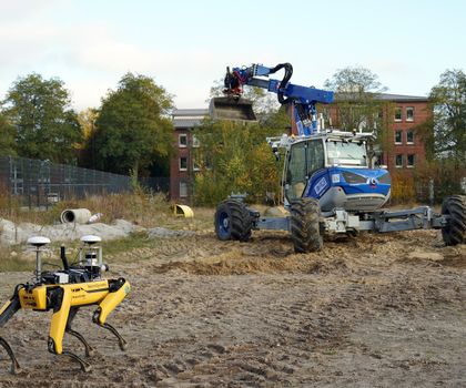 Robdekon präsentiert kollaborative Robotik auf der Baustelle Ein Roboterhund von Boston Dynamics vor einem Bagger Arter