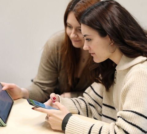 Die Studentinnen legen die Artikel im System an Zwei Studentinnen mit Tablet und Mobile phone