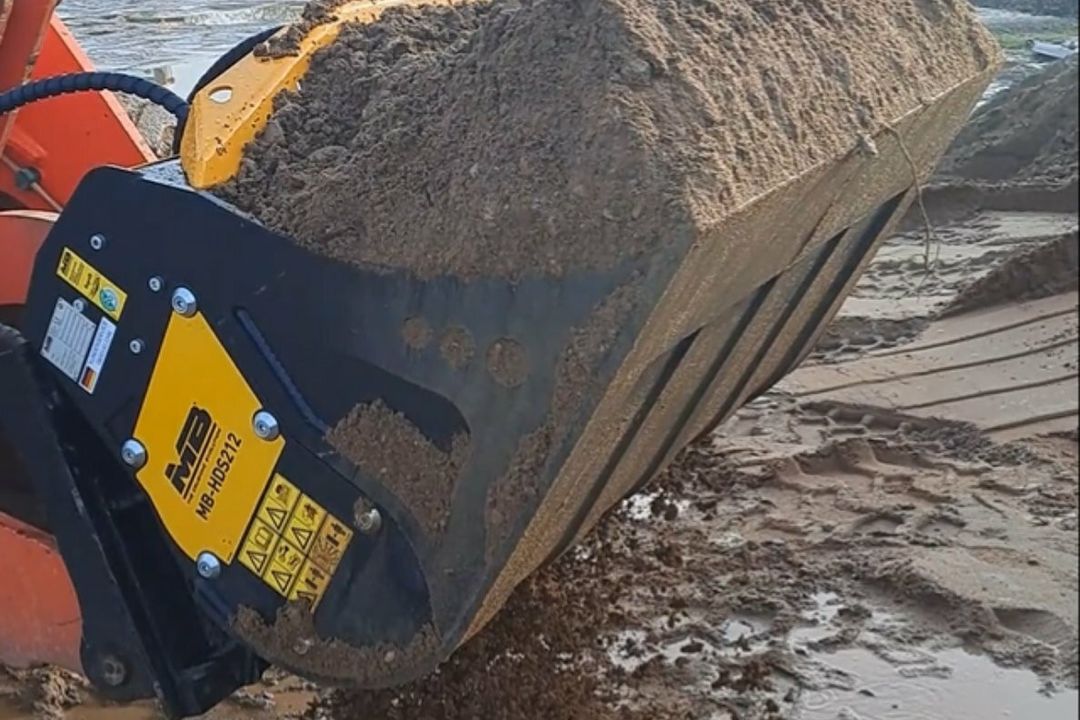 Effiziente Verfüllung im Rohr- und Kanalbau mit MB Crusher Ein Schaufelseparator von MB Crusher bewegt Aushubmaterial auf einer Baustelle