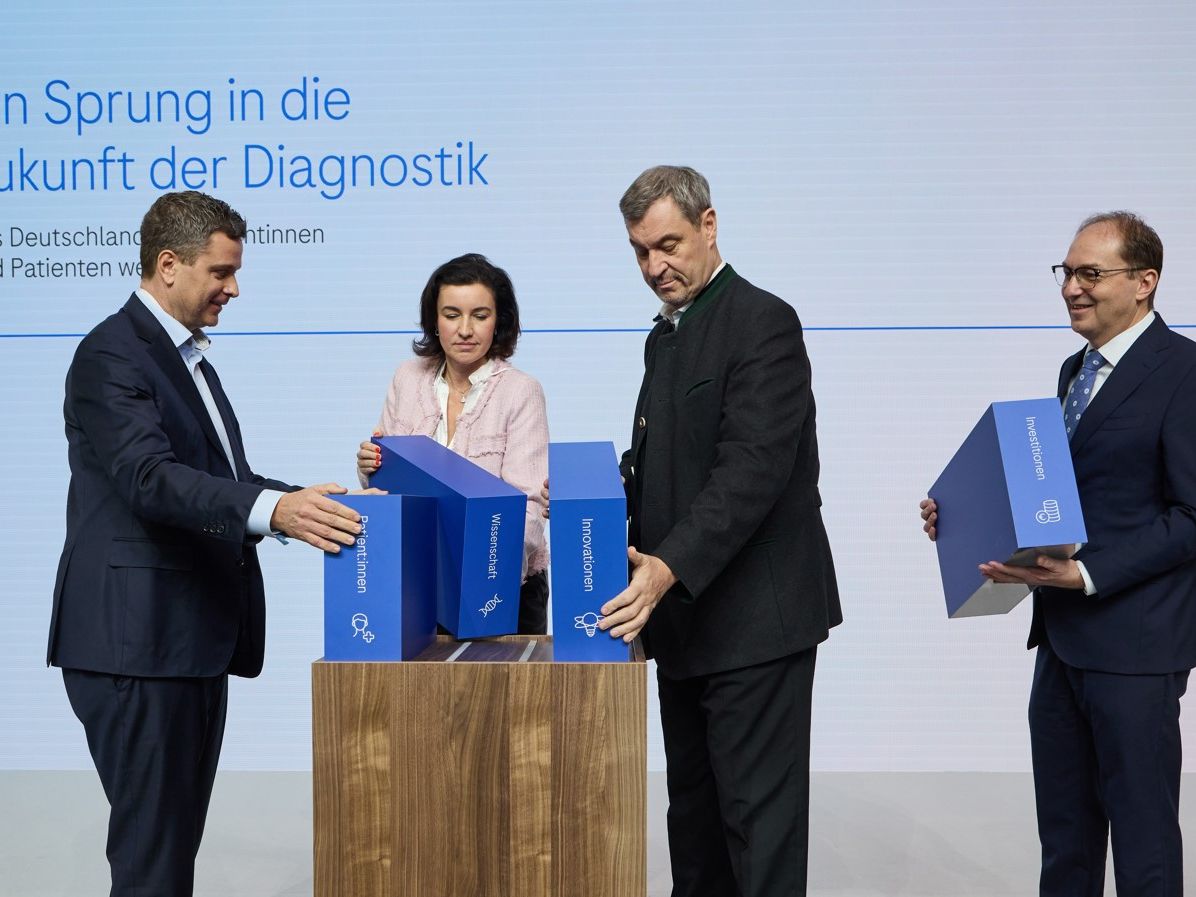 Vier Personen setzen zur Eröffnung symbolisch Bausteine zusammen