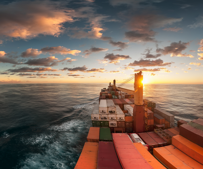 Container ship at sunrise with a cloudy sky
