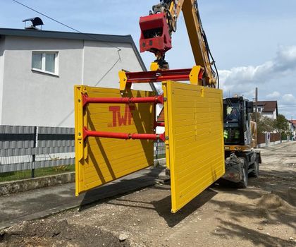 Verbaugreifer Ein TWF-Verbaugreifer, an dem Einstellboxen für den Straßenbau hängen