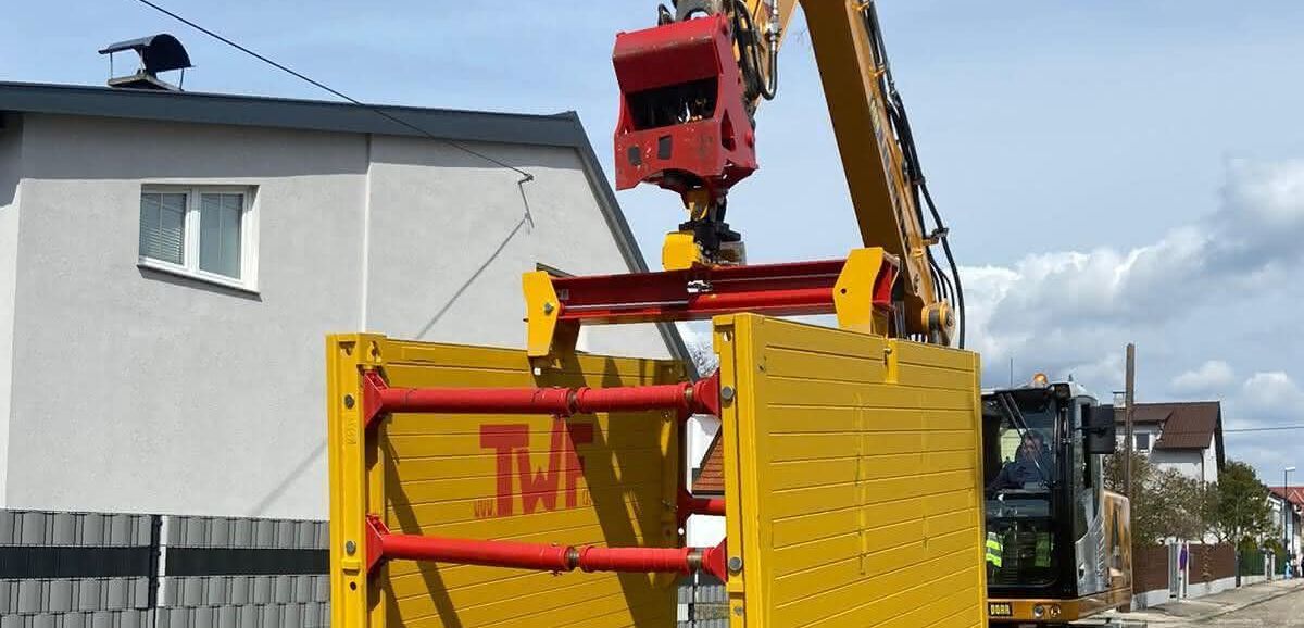 Verbaugreifer Ein TWF-Verbaugreifer, an dem Einstellboxen für den Straßenbau hängen