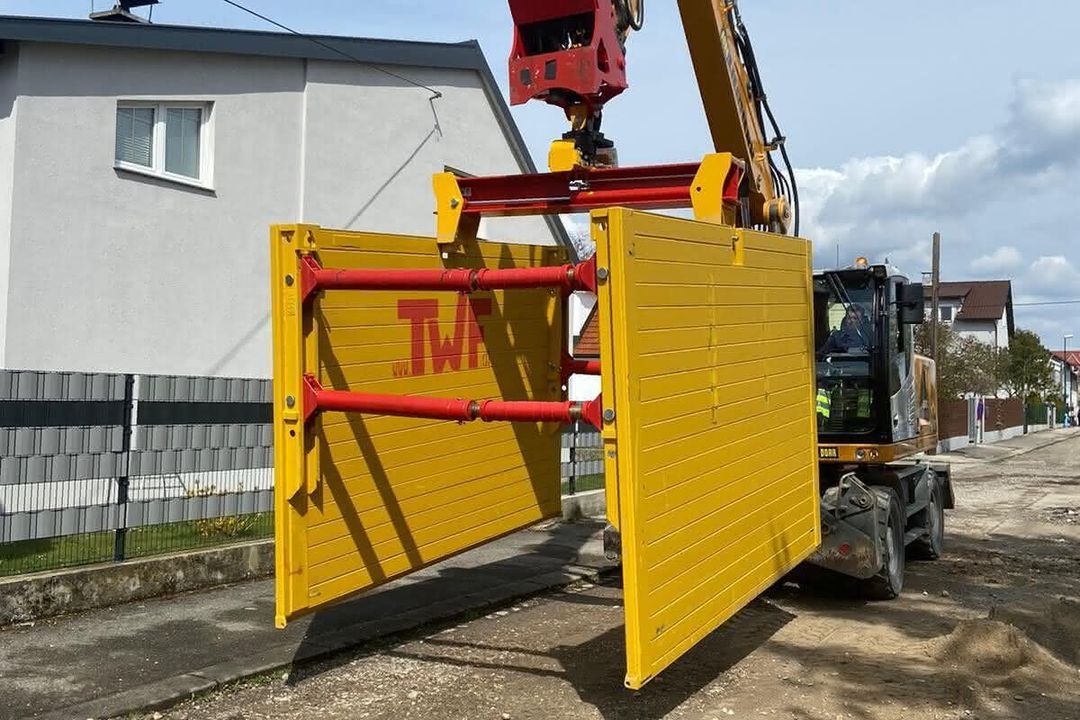 Ein TWF-Verbaugreifer, an dem Einstellboxen für den Straßenbau hängen