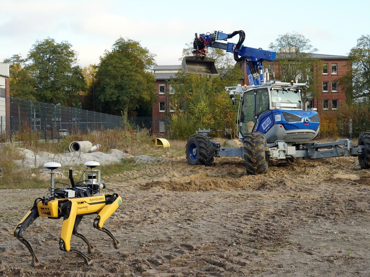 Robdekon präsentiert kollaborative Robotik auf der Baustelle Ein Roboterhund von Boston Dynamics vor einem Bagger Arter