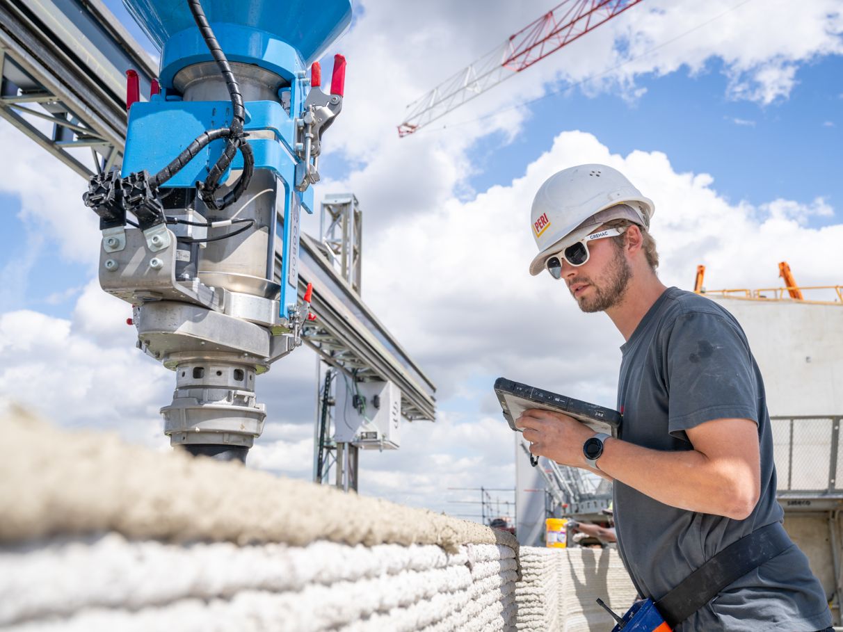 Ein Arbeiter überwacht die Druckdüse und die gedruckte Mauer