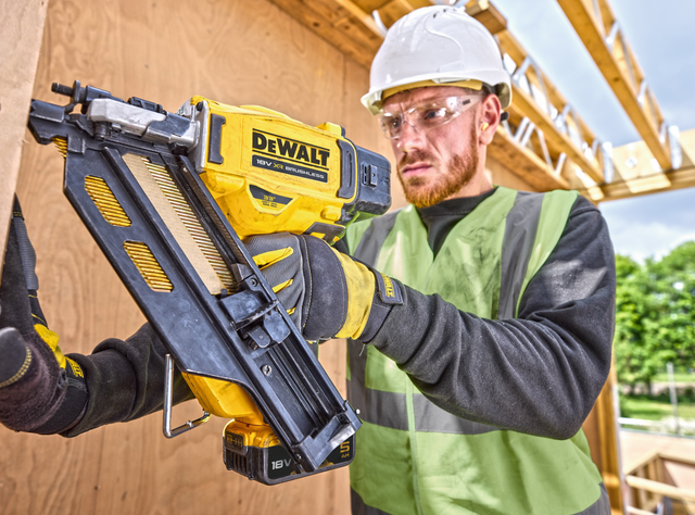 Ein Arbeiter setzt mit einer Nietmaschine Nägel in eine Holzwand
