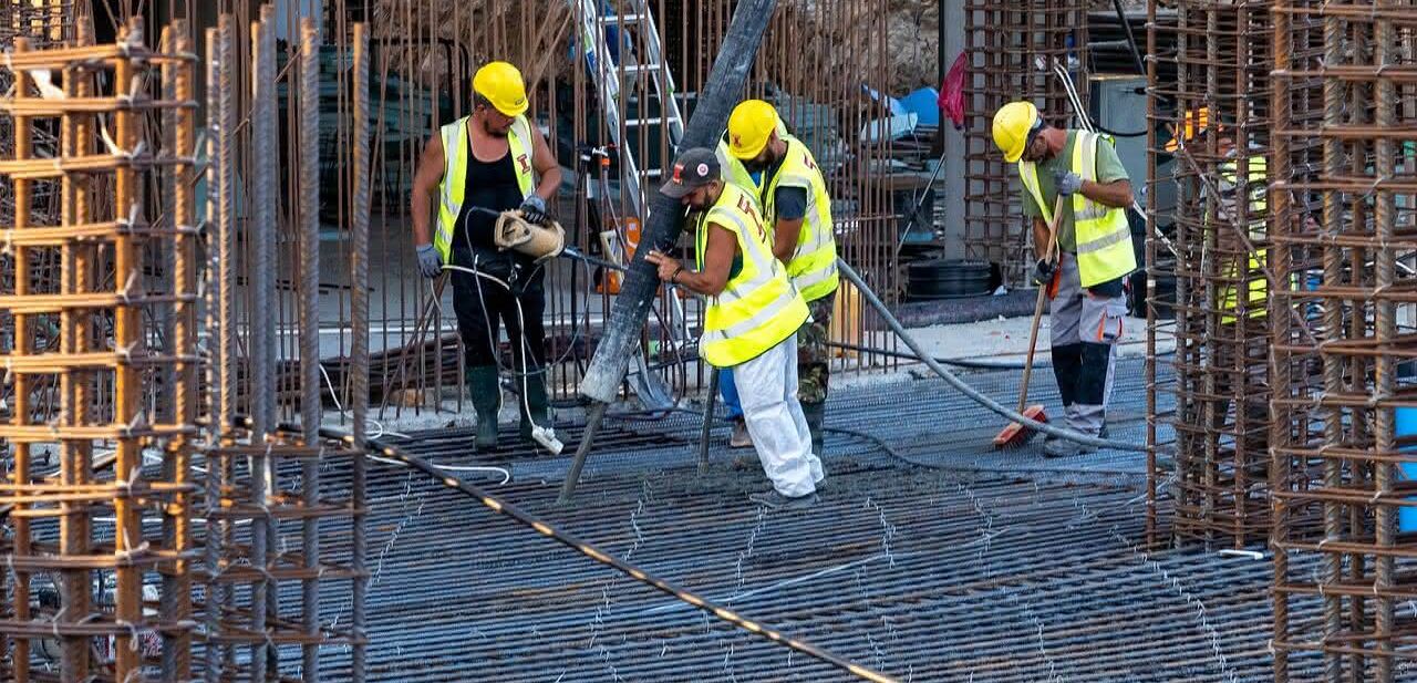 Bauarbeiter füllen Beton in den Rohbau auf einer Baustelle Bauarbeiter füllen Beton in den Rohbau auf einer Baustelle