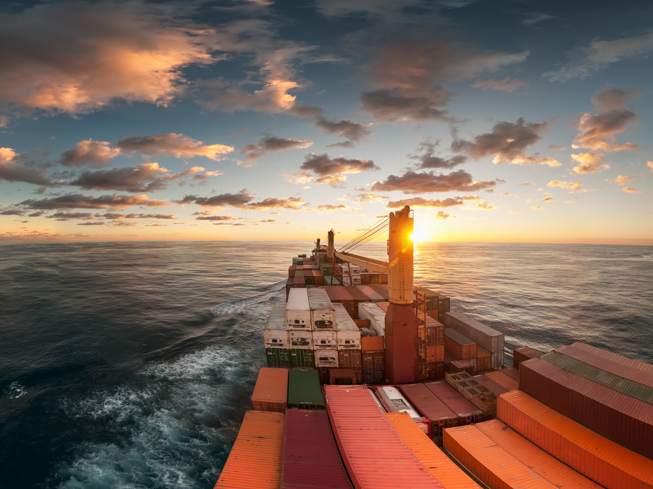 Werkzeugmaschinenbau: Mehr Aufträge, aber noch keine Trendwende Containerschiff bei Sonnenaufgang mit wolkigem Himmel