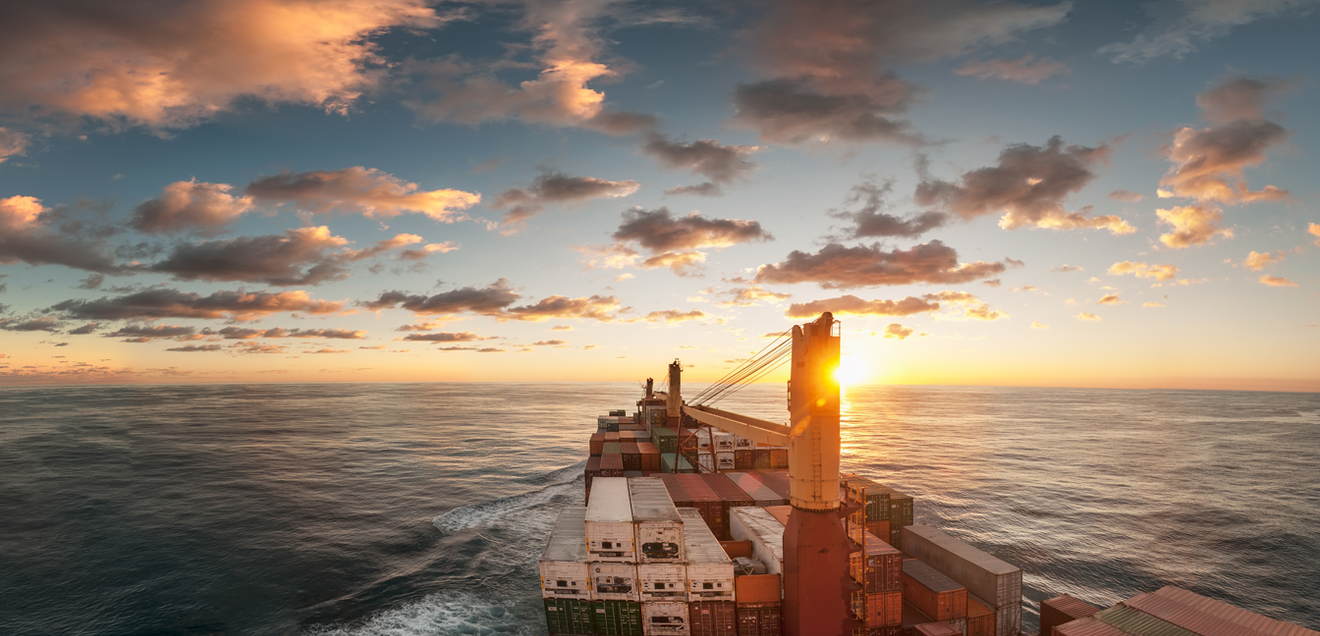 Container ship at sunrise with a cloudy sky