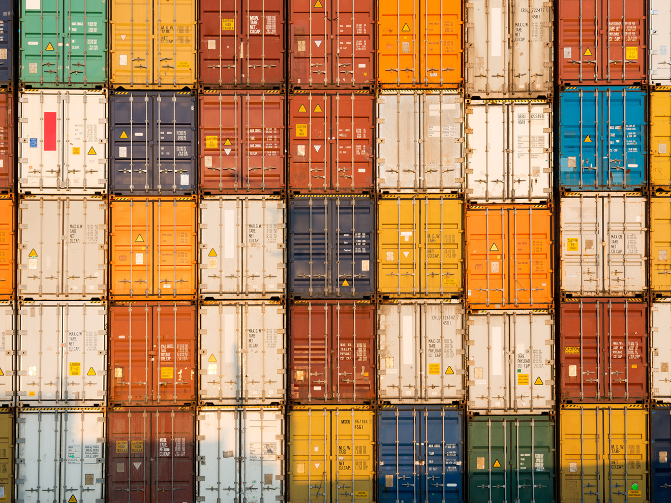 Bunte Container übereinandergestapelt füllerm das gesamte Bild aus. In der Höhe sind es 5 Container, in der Breite neun. Symbolbild für die Stimmung in der Industrie.