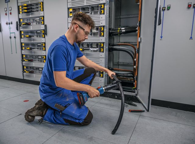 Ein Handwerker schneidet mit dem GKH 18V-50 Professional ein Kabel durch.