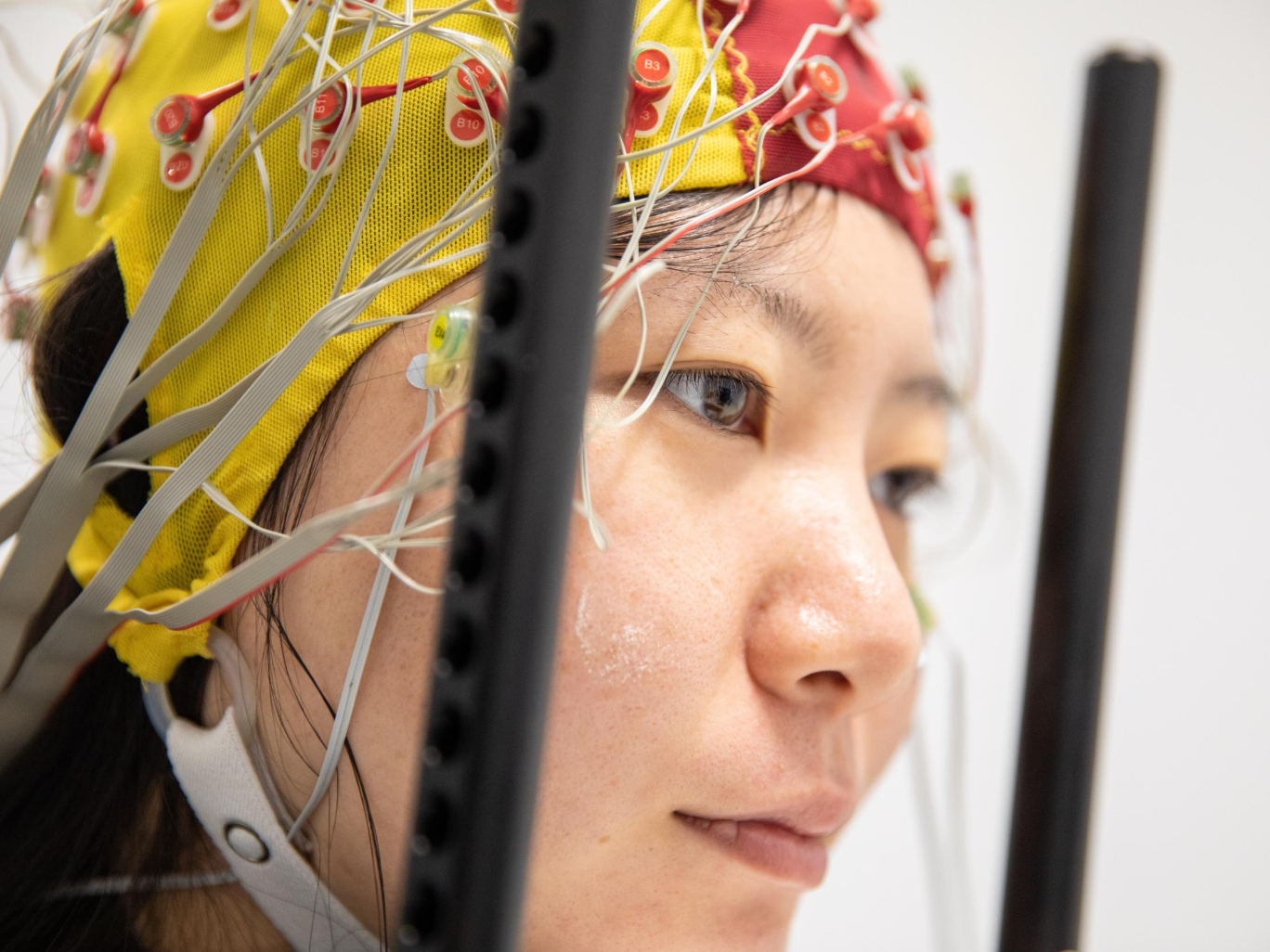 Wie das Gehirn störende Reize gezielt ausblendet Testperson mit angebrachter EEG-Haube, welche die simultane Spannungsmessung an 64 Stellen der Kopfoberfläche ermöglicht.
