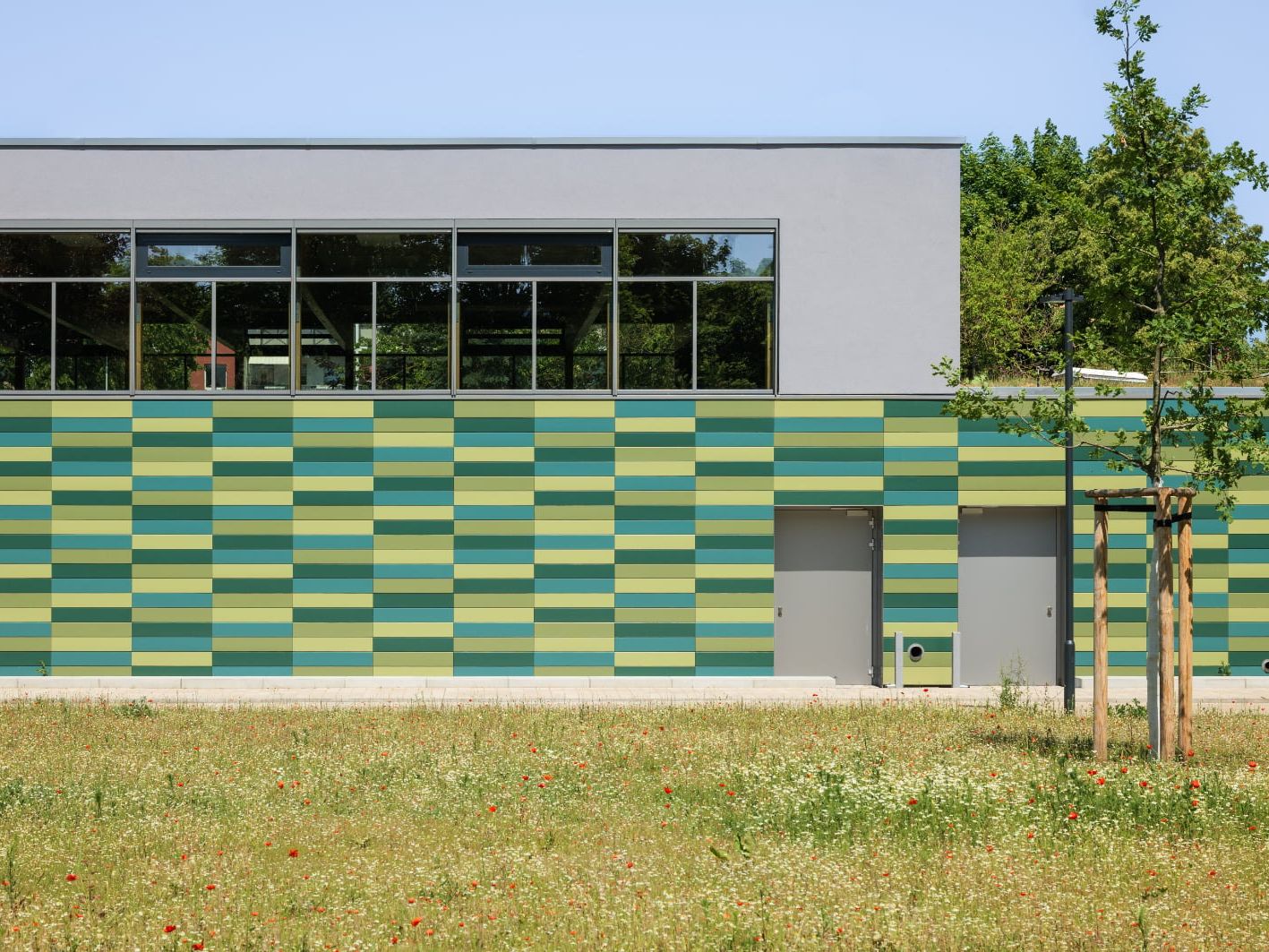 Die Tonality-Keramikfassade fügt sich harmonisch ins Schulumfeld ein. Architektur und Natur verschmelzen zu einem stimmigen Gesamtbild.