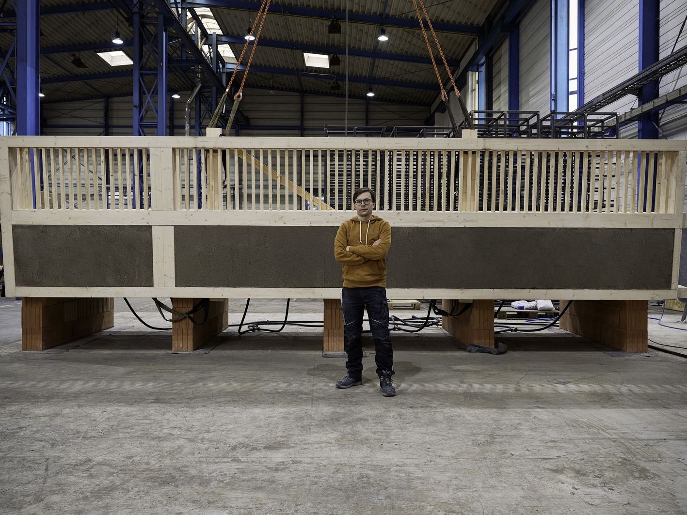 Julian Trummer vor einer Lehm-Holz-Massivdecke in einer weitläufigen Lagerhalle.