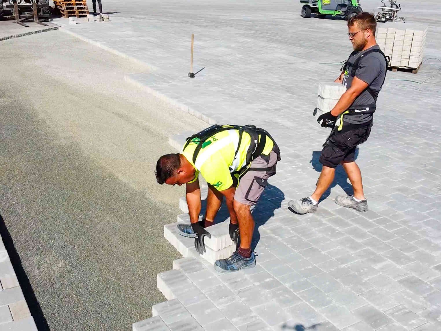 hTRIUS präsentiert: Exoskelett mit AGR-Gütesiegel Zwei Arbeiter, die Pflastersteine verlegen tragen zur Arbeitserleichterung Exoskelette von hTRIUS