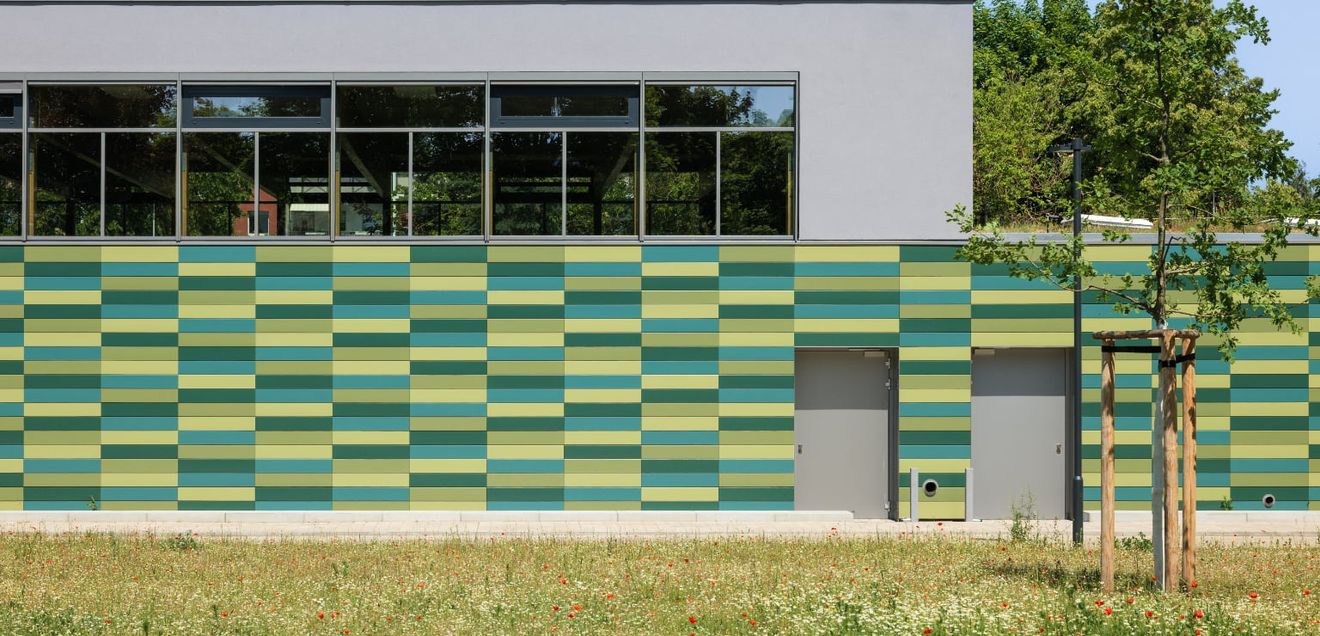 Die Tonality-Keramikfassade fügt sich harmonisch ins Schulumfeld ein. Architektur und Natur verschmelzen zu einem stimmigen Gesamtbild.