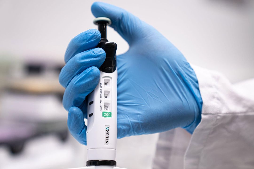 EVOLVE-Pipette von Integra in der Hand eines Labor-Mitarbeitenden
