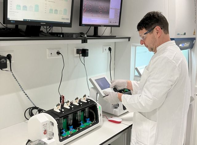 Bioreaktor im Labor mit integrierten Sensoren Forschender im Labor vor einem Bioreaktor mit integrierten Sensoren