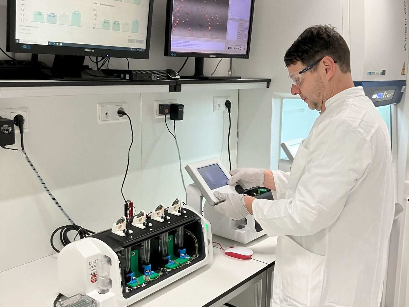 Forschender im Labor vor einem Bioreaktor mit integrierten Sensoren
