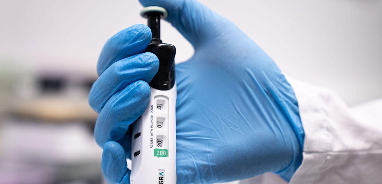 Ergonomisches Pipettieren EVOLVE-Pipette von Integra in der Hand eines Labor-Mitarbeitenden