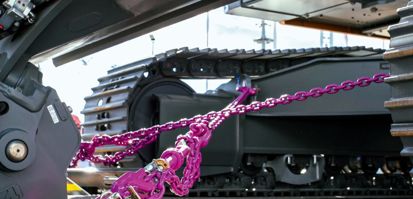 Ladungssicherung RUD Ketten RUD Ketten im typsichen Pink sichern eine Baumaschine auf einem Anhänger