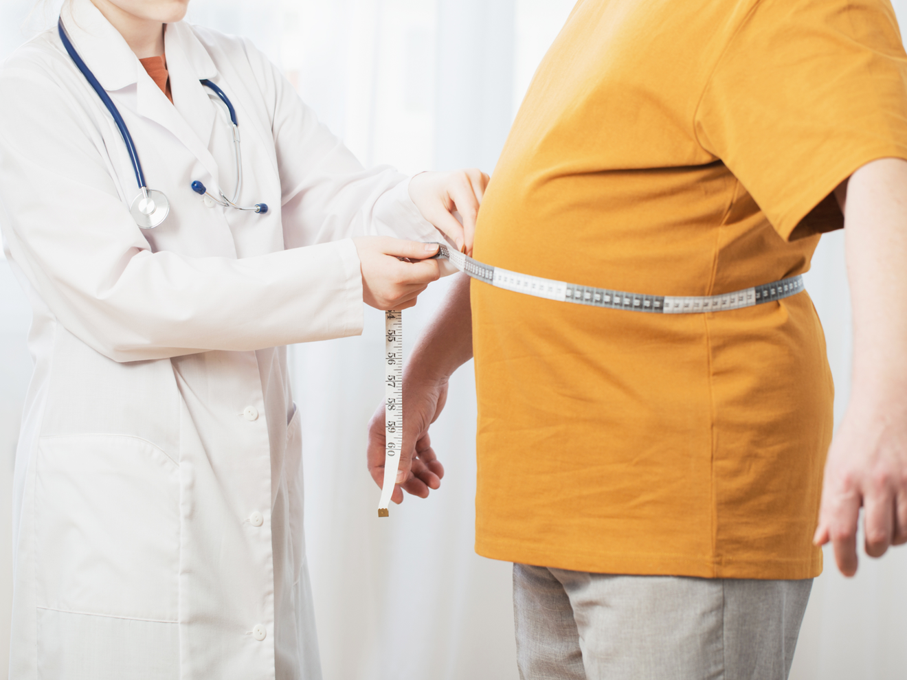 Gewicht halten nach Abnehmspritzen | Deutsche Gesellschaft für Ernährungsmedizin fordert strukturierte Ernährungsbegleitung Gewicht halten nach Abnehmspritzen: Ärztin misst Bauchumfang mit einem Maßband bei einem Patienten, der wegen Übergewicht mit der Abnehmspritze behandelt wurde