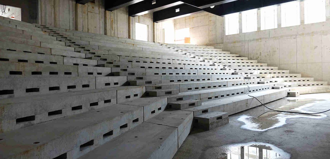Die Sitzbänke der Hörsäle gehören zu den wenigen Elementen, die in Betonfertigteilen erstellt wurden. Die große Spannweite des Saals wird durch hochwertige, schwere Stahlträger überbrückt. Die Sitzbänke der Hörsäle gehören zu den wenigen Elementen, die in Betonfertigteilen erstellt wurden. Die große Spannweite des Saals wird durch hochwertige, schwere Stahlträger überbrückt.
