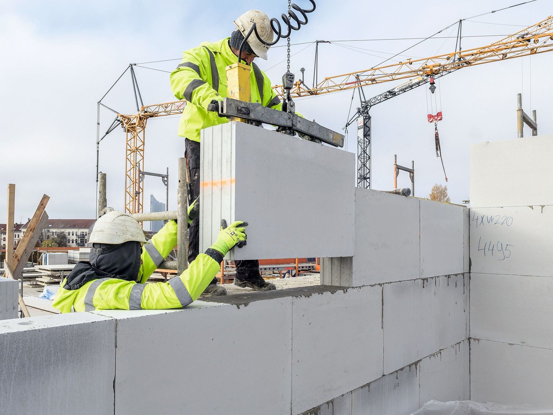 Arbeiter Arbeiter auf einer Baustelle setzen Kalksandsteinblöcke auf einer Mauer