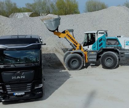 Radlader und Muldenkipper Ein wasserstoffgetriebener Radlader belädt einen Muldenkipper mit Kies