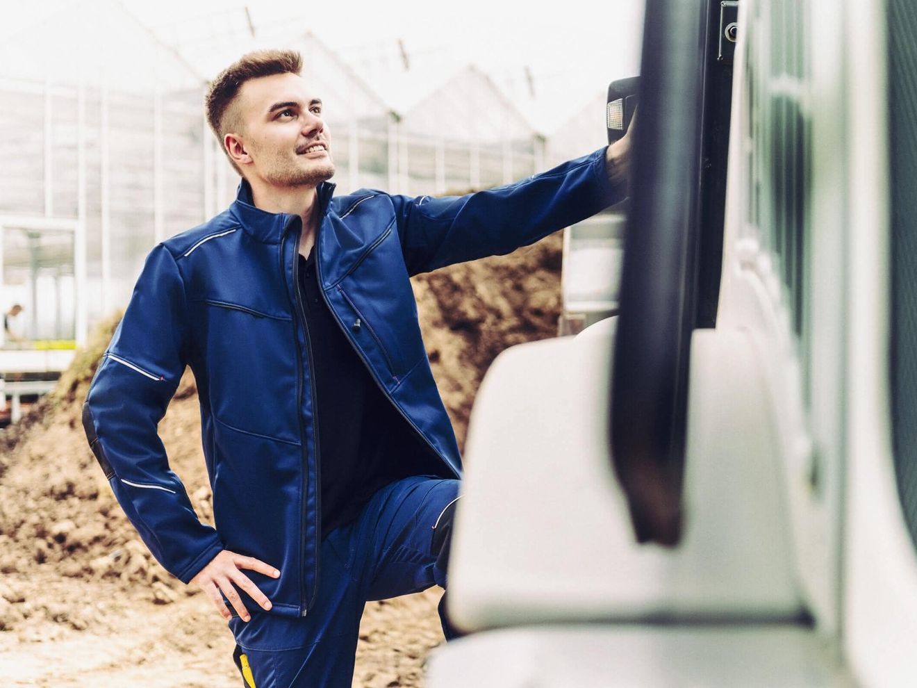 Kollektion Ein Arbeiter in blauer Arbeitskleidung von Weitblick an einer Maschine auf einer Baustelle