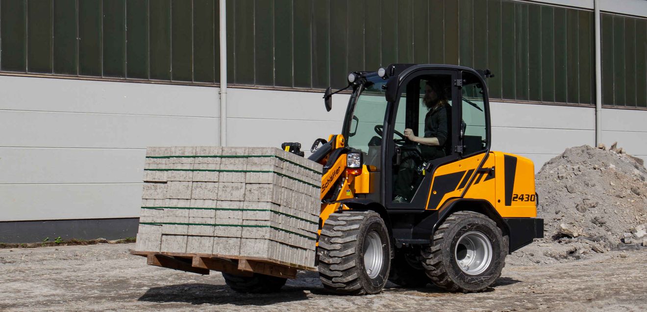 Ein neuer Schäffer Kompakt-Radlader 2430-2 transportiert Pflasterplatten