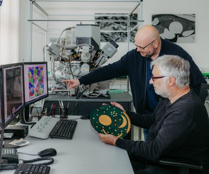 Dr. Christian-Heinrich Wunderlich vom Landesamt für Denkmalpflege und Archäologie Sachsen-Anhalt (vorn) mit einer Replik der Himmelsscheibe von Nebra und Prof. Dr. Thorsten Halle im Labor auf dem Campus der Uni Magdeburg, wo die Untersuchungen stattfanden.