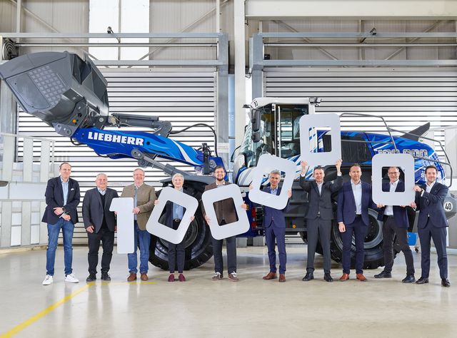 Gruppenbild mit den Vertretern aller beteiligten Firmen in einer Werkshalle vor dem Liebherr-Radlader mit blau-weißer Lackierung