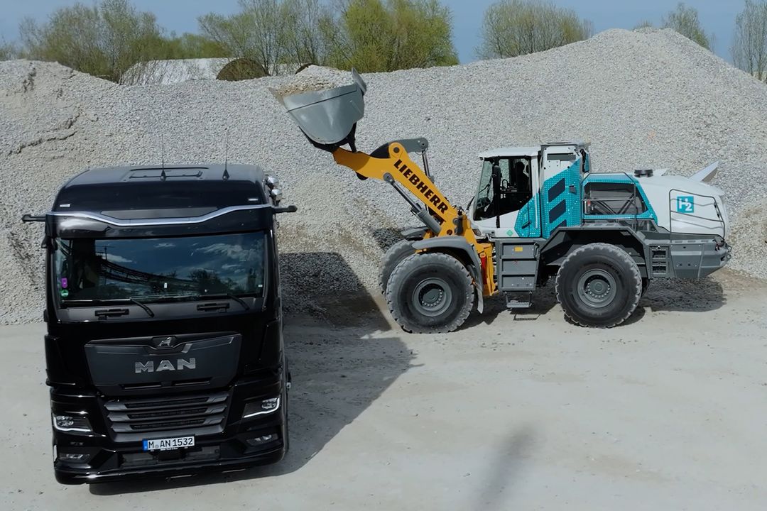 Ein wasserstoffgetriebener Radlader belädt einen Muldenkipper mit Kies