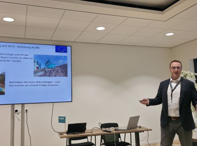 Hanns Markus Renz, Business Director DCH bei Kobelco vor einer Leinwand im europäischen Hauptsitz von Kobelco