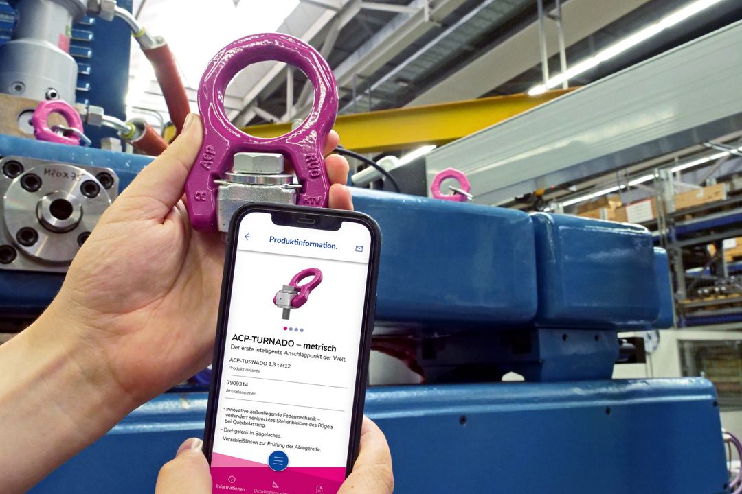 RUD BUDDYtron App: Digitaler Berater für Hebevorgänge Ein Mitarbeiter liest an einem lila Bauteil mithilfe der App und seines Smartphones Daten aus