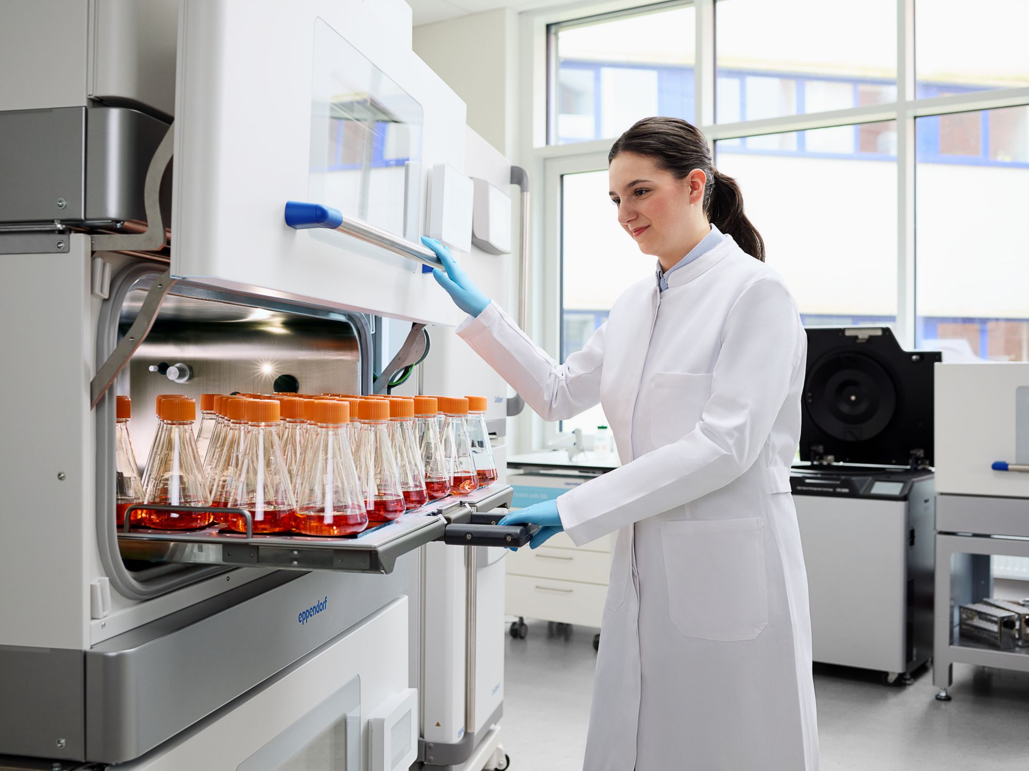 Labormitarbeiterin am CO2 Inkubationsschüttler mit integrierter Sterilisationsfähigkeit Labormitarbeiterin am CO2 Inkubationsschüttler mit integrierter Sterilisationsfähigkeit