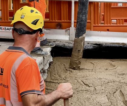 Arbeiter Ein Arbeiter beobachtet, wie Beton in eine Baugrube läuft