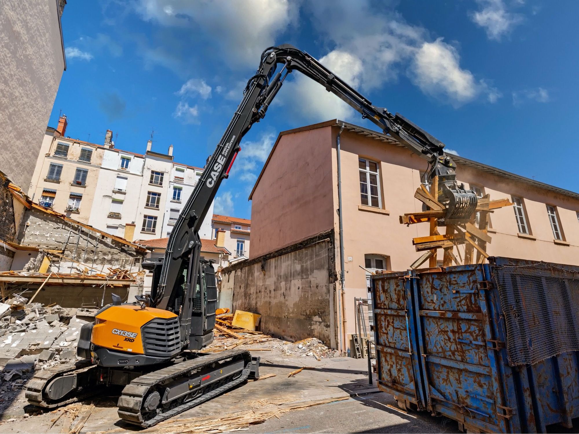 Der neue Abbruchbagger von Case wie er mit einem Greifer Abbruchmaterial in einen Container legt