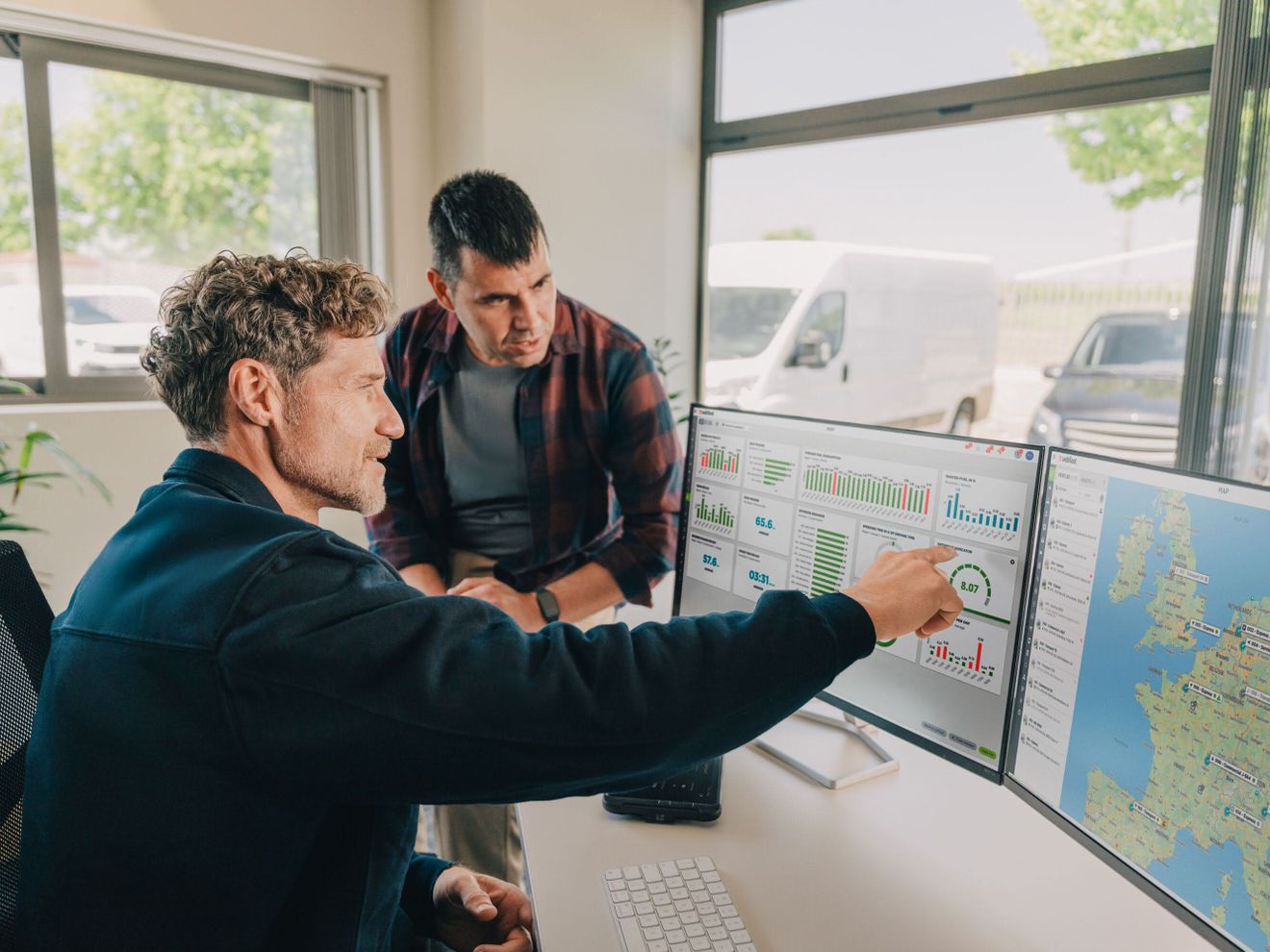 Flottenmanagement 2026 Zwei Männer schauen zwei Monitoren auf die Flottenmanagementsoftware von Webfleet
