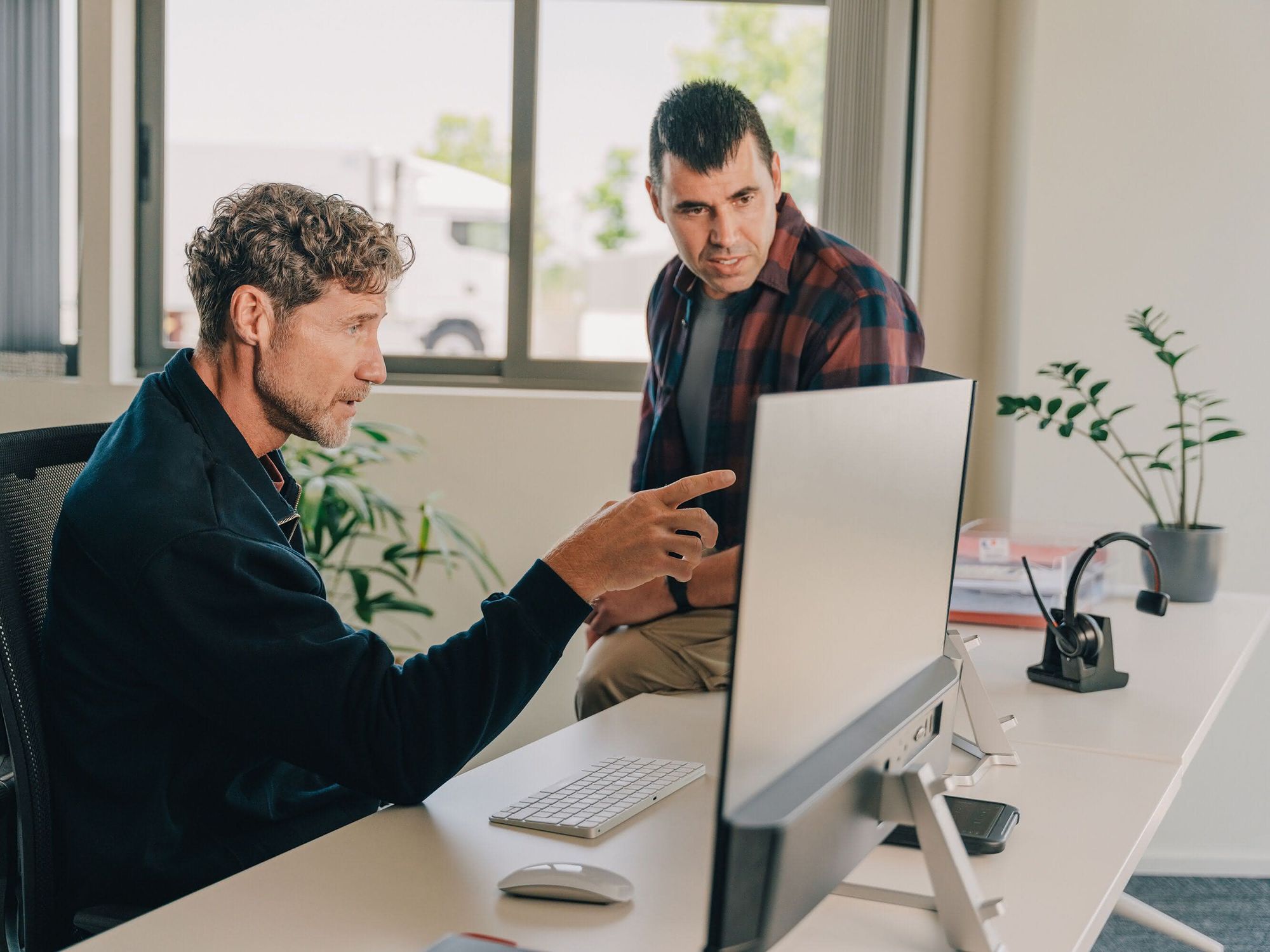 Zwei männliche Mitarbeitende managen die Telematik und das Fuhrparkmanagement mit Webfleet