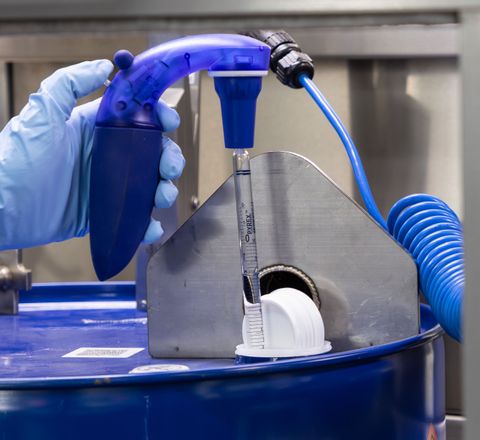Hand eines Labormitarbeitenden entnimmt Probe mit spezieller Vorrichtung für Flüssigkeiten.