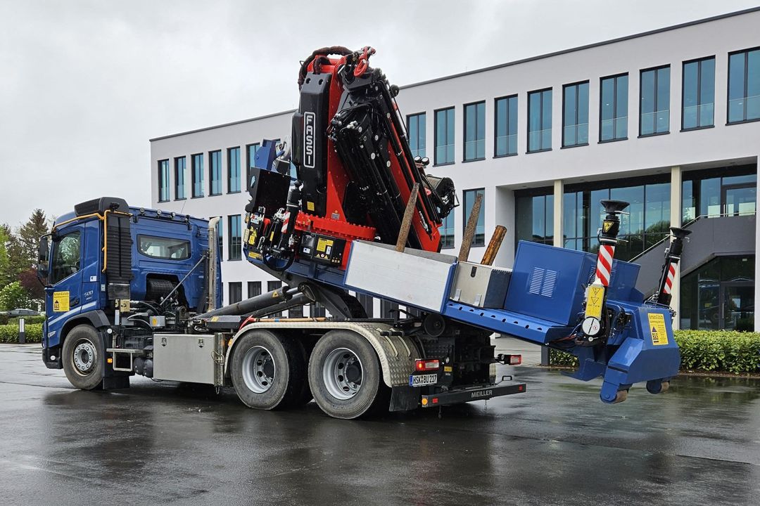 Ladekran von Fassi auf Abrollcontainer-Chassis Der Fassi F7 10RA.2.28 xhe-dynamic auf dem Abroll-Chassis vor einem Werksgebäude
