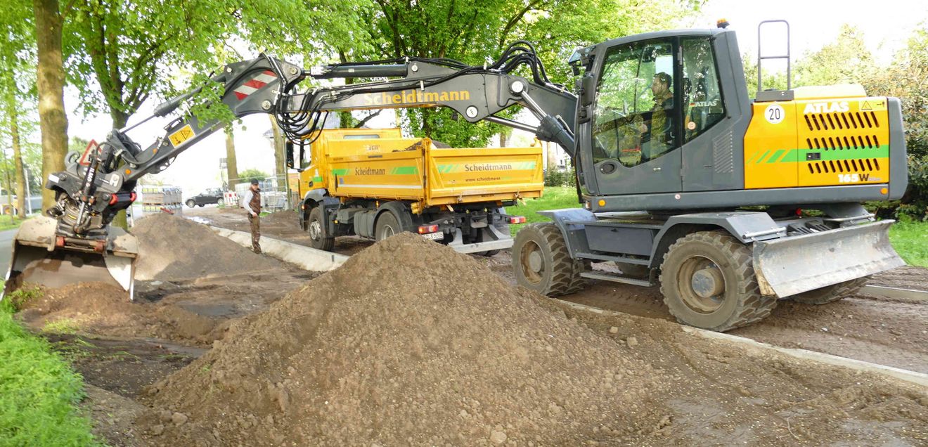 Ein Atlas 165 W befüllt einen Lastwagen mit Material einer Baustelle am Bankett einer Allee