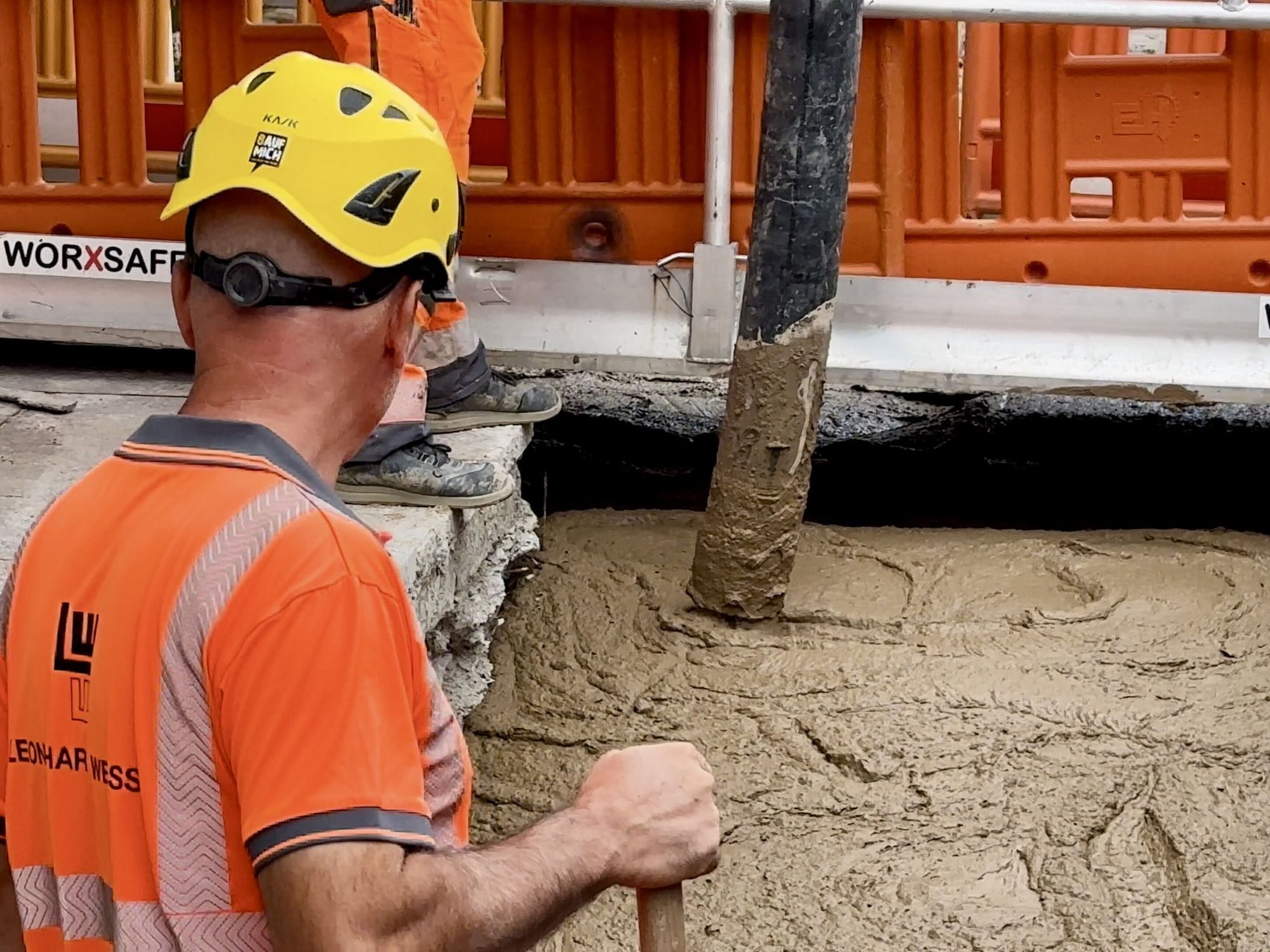 Ein Arbeiter beobachtet, wie Beton in eine Baugrube läuft